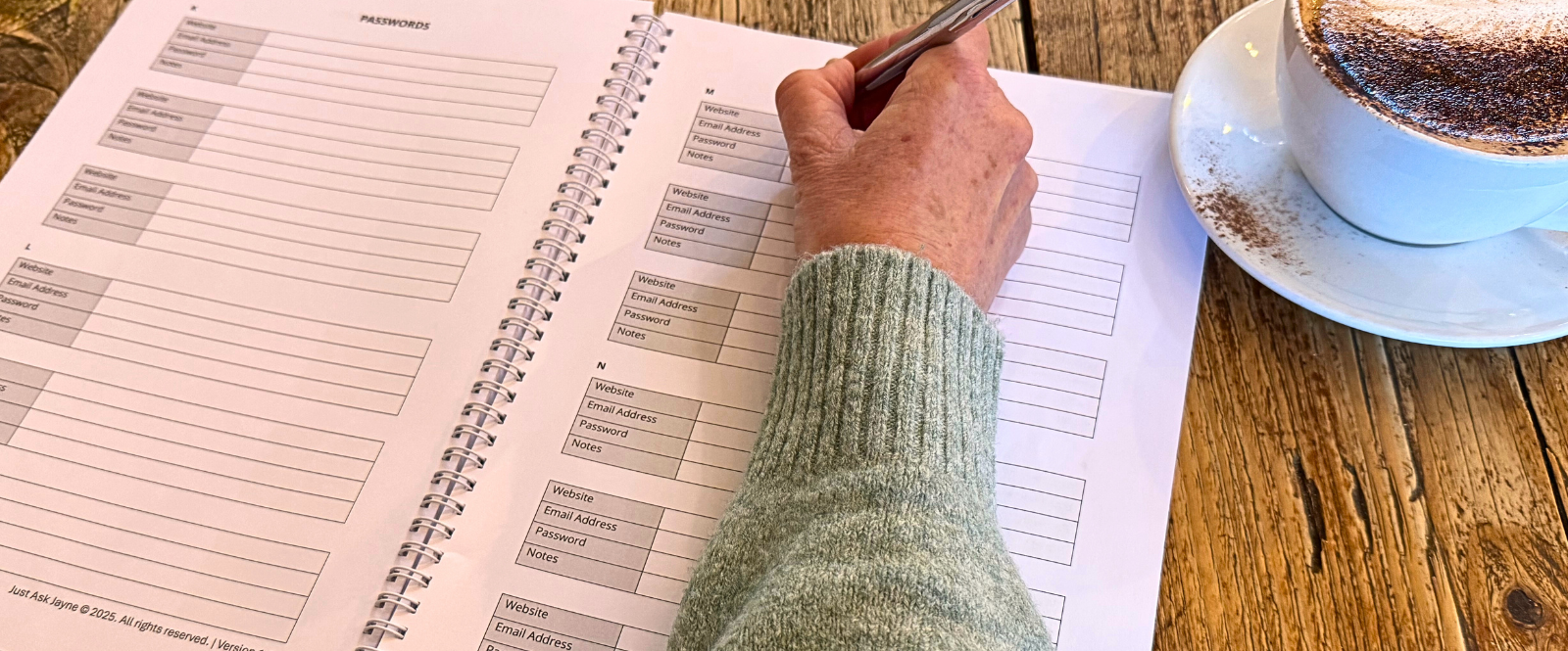 Picture shows someone filling in some information in Jayne's Peace of Mind Planner with a cup of coffee on the table too